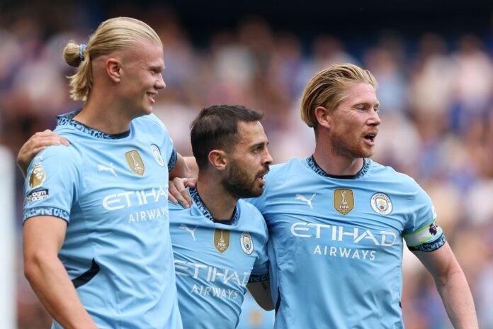 LONDON, ENGLAND - AUGUST 18: Erling Haaland of Manchester City celebrates scoring his team's first goal with teammates Bernardo Silva and Kevin De Bruyne during the Premier League match between Chelsea FC and Manchester City FC at Stamford Bridge on August 18, 2024 in London, England.