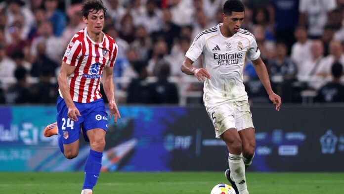 Jude Bellingham of Real Madrid runs with the ball from Robin Le Normand of Atletico de Madrid during the Spanish Super Cup Semi-Final match between Real Madrid and Atletico Madrid at King Abdullah Sports City Hall Stadium on January 08, 2026 in Jeddah, Saudi Arabia.